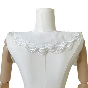Close-up detail of white double-layer lace doll collar with embroidered scalloped edge