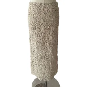 Detail of beige cotton lace crochet maxi skirt with hollow floral embroidery pattern.