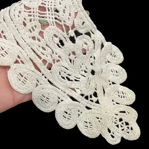 Close-up macro view of a white cotton lace collar featuring intricate embroidery details