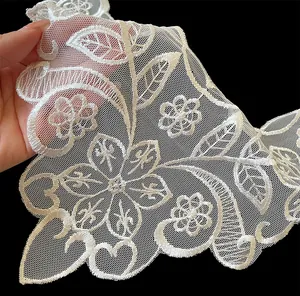 Macro detail of white embroidered floral lace faux collar with intricate mesh texture