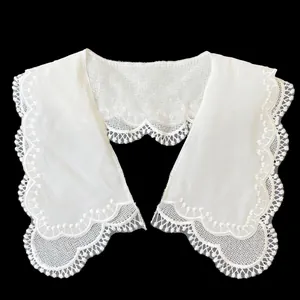 Close-up detail of white double-layered lace doll collar with scalloped embroidery