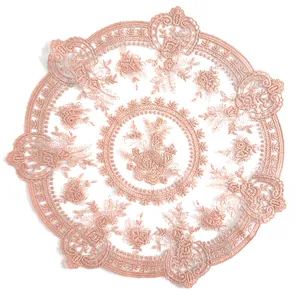 Detail view showing the intricate floral embroidery on a vintage pink lace placemat.