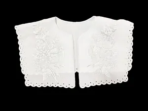 Close-up detail of a white eyelet embroidered lace doll collar with floral patterns