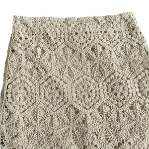Detailed macro view of beige crochet hollow lace floral pattern on a summer knit skirt