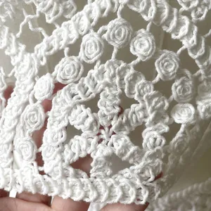 Macro close-up detail of intricate white cotton lace crochet embroidery floral pattern.