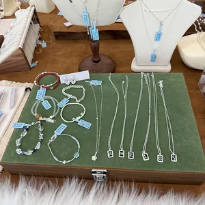 Detailed macro view of various S925 silver jewelry and square letter pendant necklaces.
