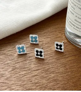 Close-up of s925 silver quatrefoil stud earrings with blue turquoise and black onyx details.