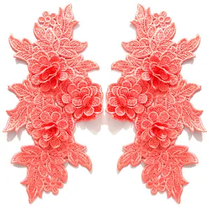 Detailaufnahme symmetrischer korallenrosa Spitzenstickerei-Blumenaufnäher mit 3D-Textur.