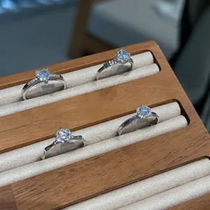 Detail view of four silver rings with diamond-like stones in a wooden display tray