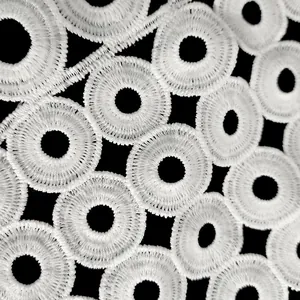 Vue macro détaillée de dentelle brodée en soie de lait blanche aux motifs circulaires