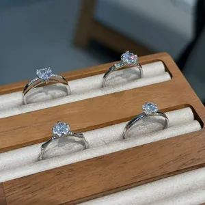 Four elegant S925 silver rings with sparkling stones displayed in a wooden jewelry box