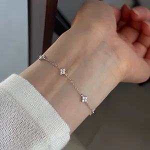 Detailed view of a silver four-leaf clover bracelet with sparkling stones on a wrist.