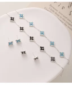 Detail view of silver clover earrings and necklace set with black and blue stones
