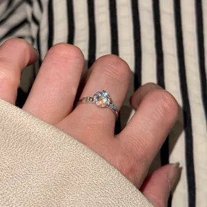 Close-up of sparkling s925 silver ring with eight hearts and arrows cut stone on finger