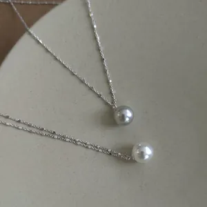Close-up detail of 925 sterling silver necklaces featuring round white and grey pearls.