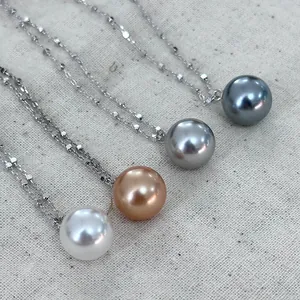 Detail view of four colored round pearl necklaces with 925 sterling silver chains on canvas.