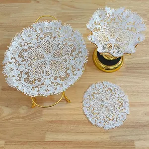 Detailansicht zarter weißer Platzsets aus Spitzenstickerei auf einem Holztisch.