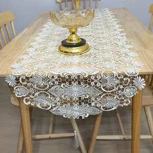 Macro detail of a white hollow-out lace table runner with tassel on wooden table