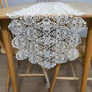 Detail of white water-soluble lace table runner with 3D floral embroidery and tassel