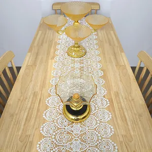 Top-down view of white lace table runner with intricate floral patterns on a wooden table