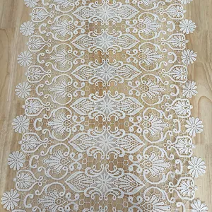 Close-up detail of white hollow-out lace table runner featuring intricate floral embroidery