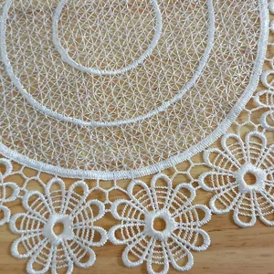 Detailed macro view of white embroidered lace placemat featuring floral patterns.