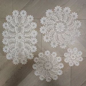 Set of four elegant white embroidered lace doilies and coasters on a wooden surface