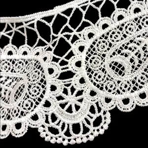 Macro view of white polyester embroidered lace detail with hollowed-out patterns