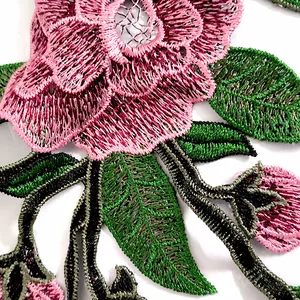 Détail macro de dentelle brodée fleurie de style ethnique avec pétales roses et feuilles vertes