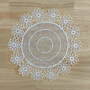 White circular lace embroidery placemat with hollow-out floral pattern on wood background