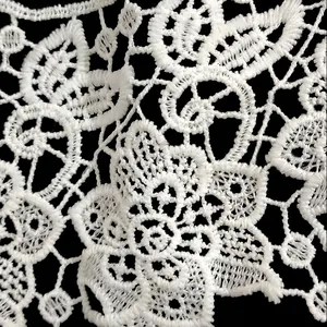 Macro view of white milk silk embroidered lace featuring an intricate hollow floral design