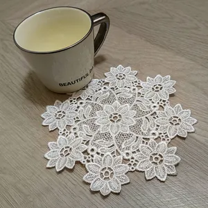 Detailed view of a white lace embroidered coaster under a ceramic mug on a wooden table