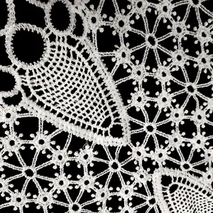 Détail macro de l'applique en dentelle creuse brodée en soie de lait blanche et fleurs