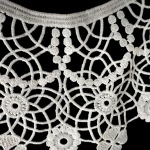 Macro detail of white milk silk embroidered lace collar with hollow floral patterns