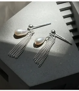 Détail de boucles d'oreilles en argent avec pampilles et perles naturelles