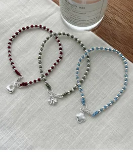 Close-up detail of S925 silver beaded cord bracelets featuring clover and bow charms.