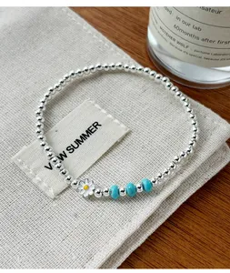 Gros plan d'un bracelet marguerite en argent 925 avec perles turquoise sur pochon.