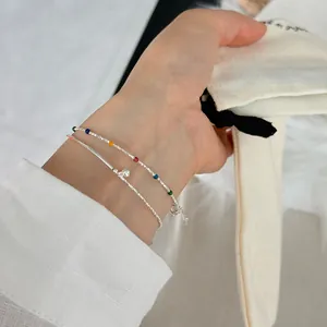 Close-up of layered s925 silver bracelet with colorful enamel beads and ball charm
