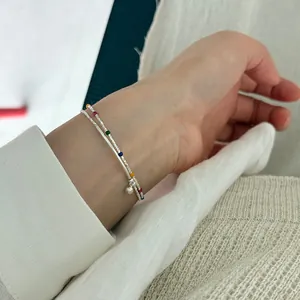 Close-up of S925 silver beaded bracelet with colorful enamel and a small ball charm on wrist.