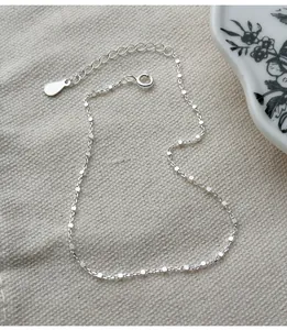 Detailansicht eines minimalistischen Fußkettchens aus 925er Silber mit Quadratgliedern.