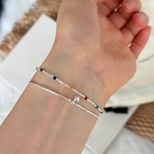 Close-up detail of s925 silver bracelet with colorful beads and small ball charm on wrist