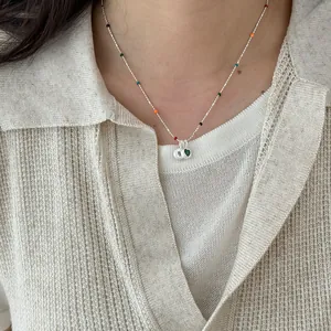Close-up of a delicate s925 silver necklace featuring a heart pendant and colorful beads