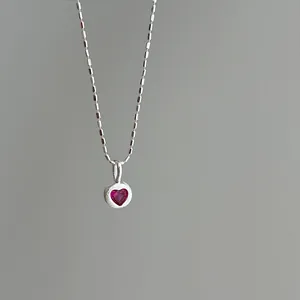 Close-up of a delicate s925 silver necklace featuring a radiant ruby heart pendant.