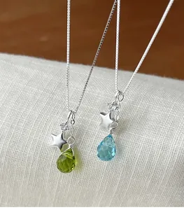 Detail view of silver necklaces featuring polished star charms and glass teardrop pendants