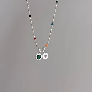 Close-up of s925 silver heart pendants with green and pink stones on beaded chain