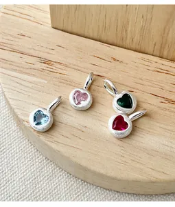 Detailed macro view of s925 silver heart charms with colorful zircon gemstones.