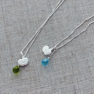 S925 sterling silver apple and crystal teardrop pendant necklaces on a linen fabric