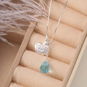 Close-up of silver irregular apple pendant and blue waterdrop gemstone necklace