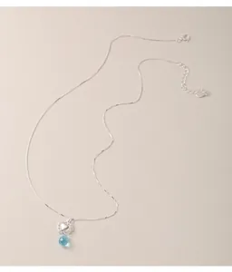 Detailed macro view of an S925 sterling silver heart necklace with a blue drop bead