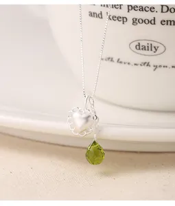 Macro detail of S925 silver heart and green waterdrop pendants with matte finish.